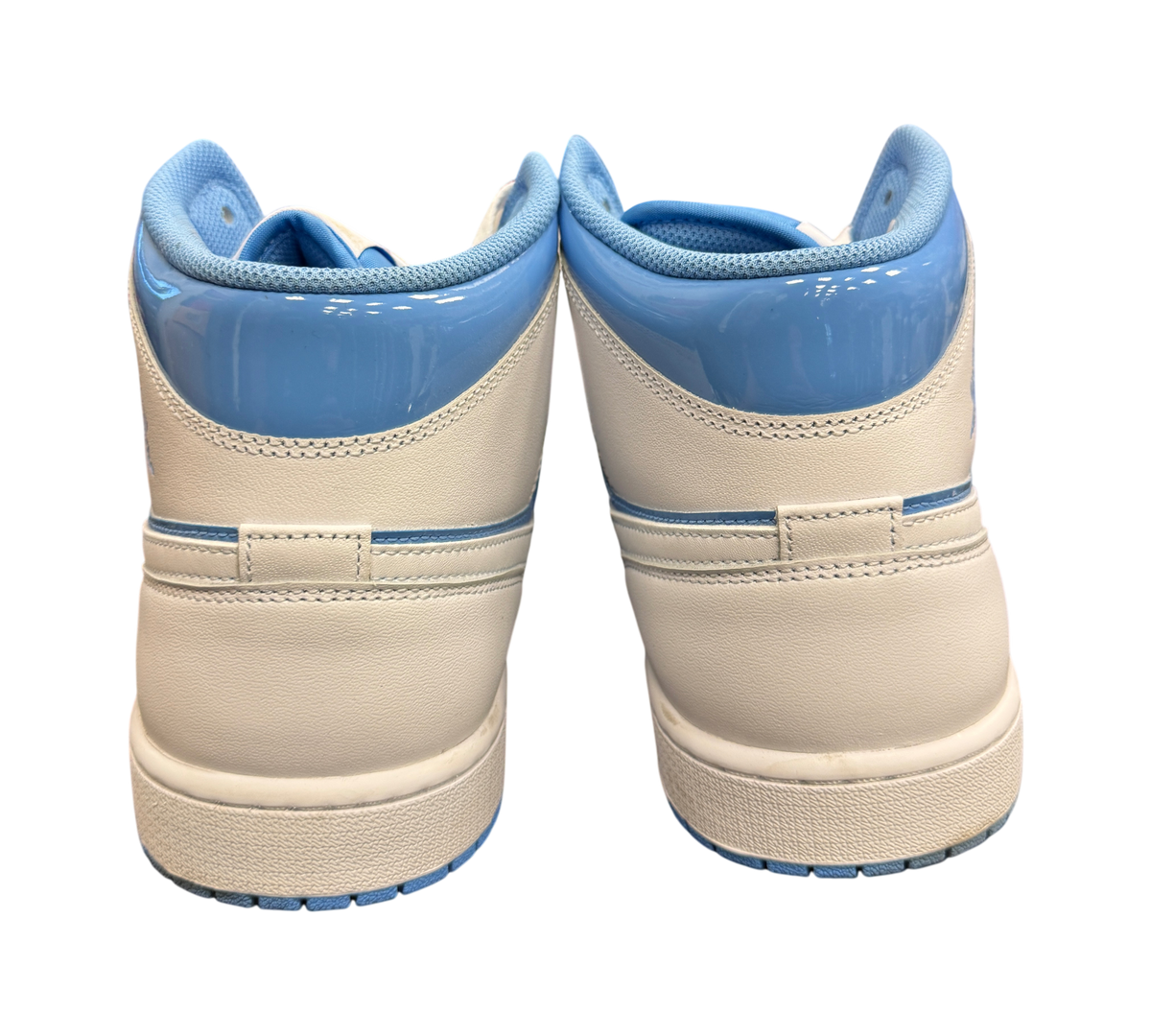 Genesis Boutique Air Jordan 1 Mid SE Legend Blue sneakers seen from the back, featuring white leather and light blue trim.