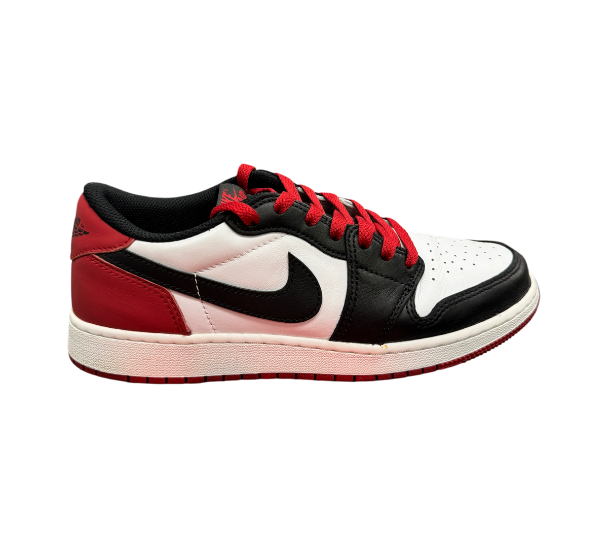 Genesis Boutique Jordan 1 Low Black Toe sneakers featuring white, black, and red leather panels with red laces.