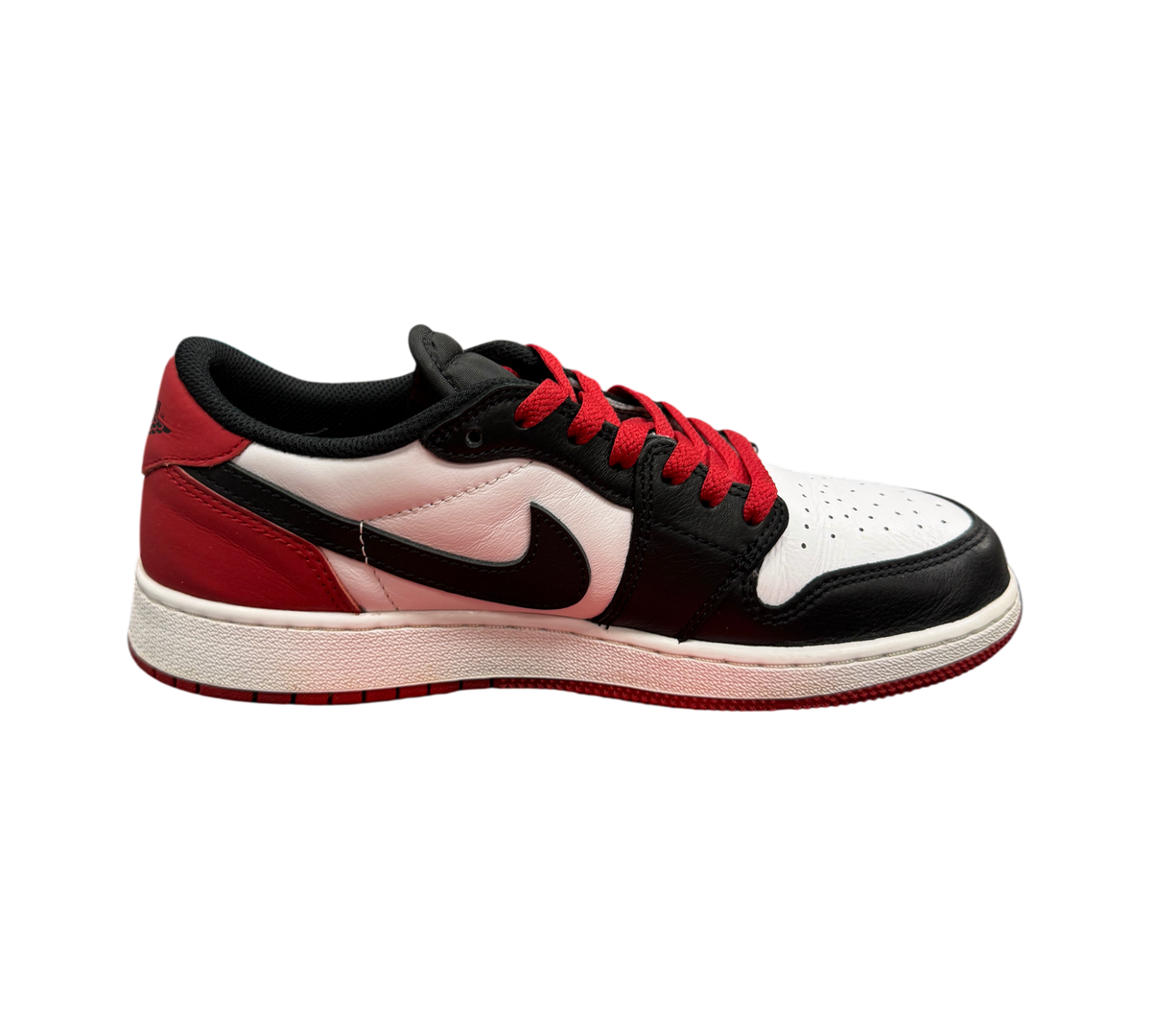 Genesis Boutique Jordan 1 Low Black Toe sneakers featuring white, black, and red leather panels with red laces.