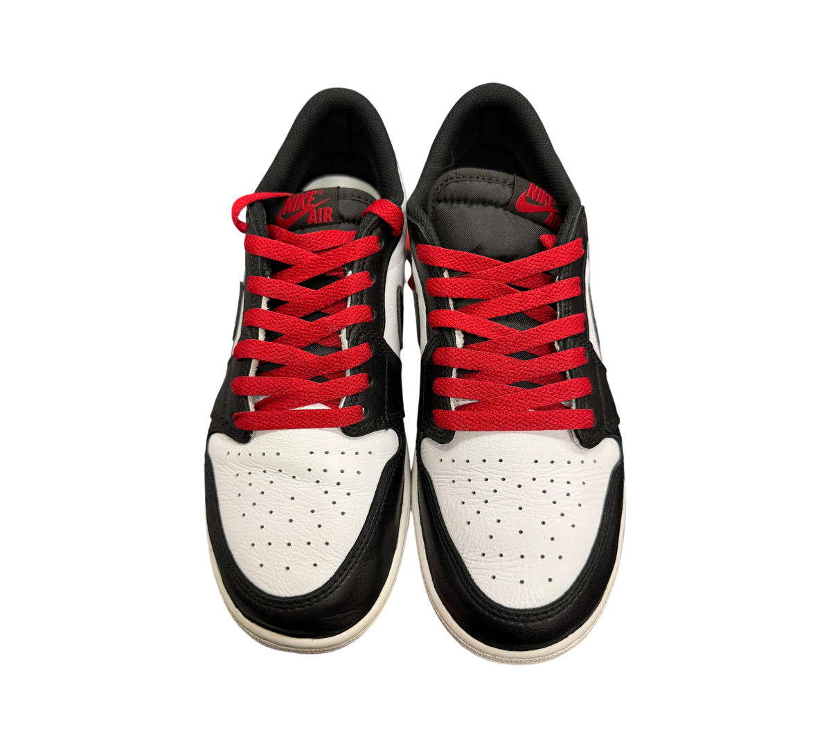Genesis Boutique Jordan 1 Low Black Toe sneakers featuring white leather, black overlays, and vibrant red laces.