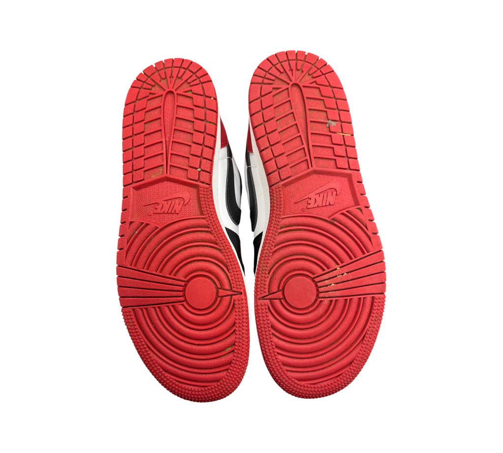 Genesis Boutique Jordan 1 Low Black Toe sneakers showing red rubber outsoles with circular traction patterns