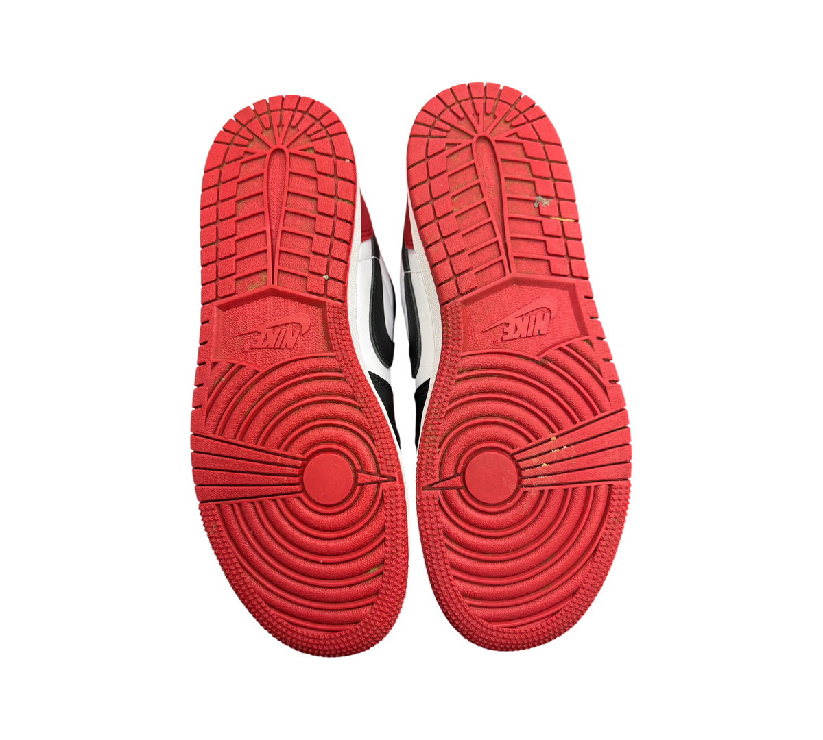 Genesis Boutique Jordan 1 Low Black Toe sneakers showing red rubber outsoles with circular traction patterns