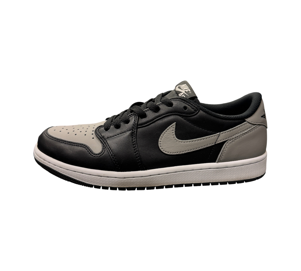 Genesis Boutique Jordan 1 Low Shadow sneakers in black and grey leather on a glass display case in a retail store.
