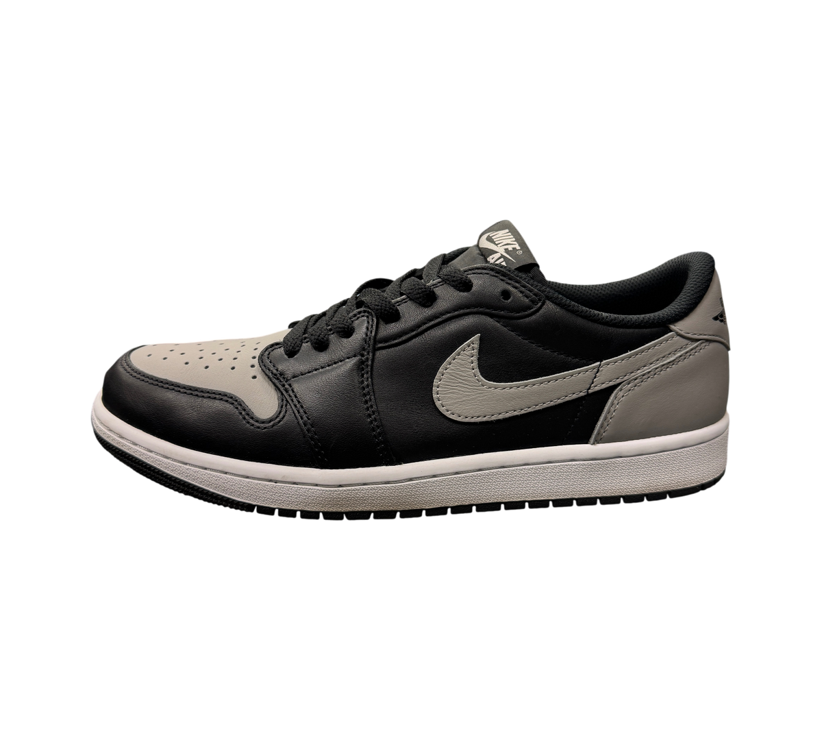 Genesis Boutique Jordan 1 Low Shadow sneakers in black and grey leather on a glass display case in a retail store.