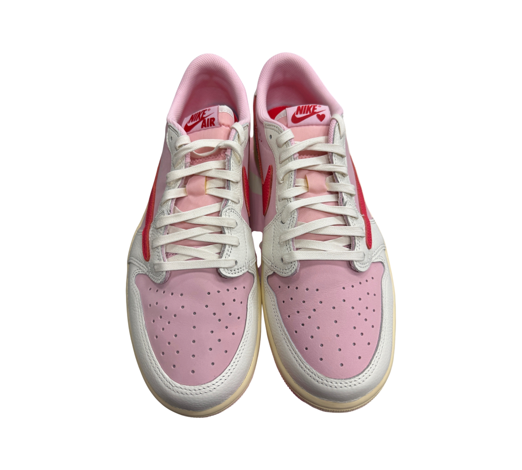 Genesis Boutique Jordan 1 Low Travis Scott Tropical Pink sneakers featuring pink leather, red swooshes, and white laces.
