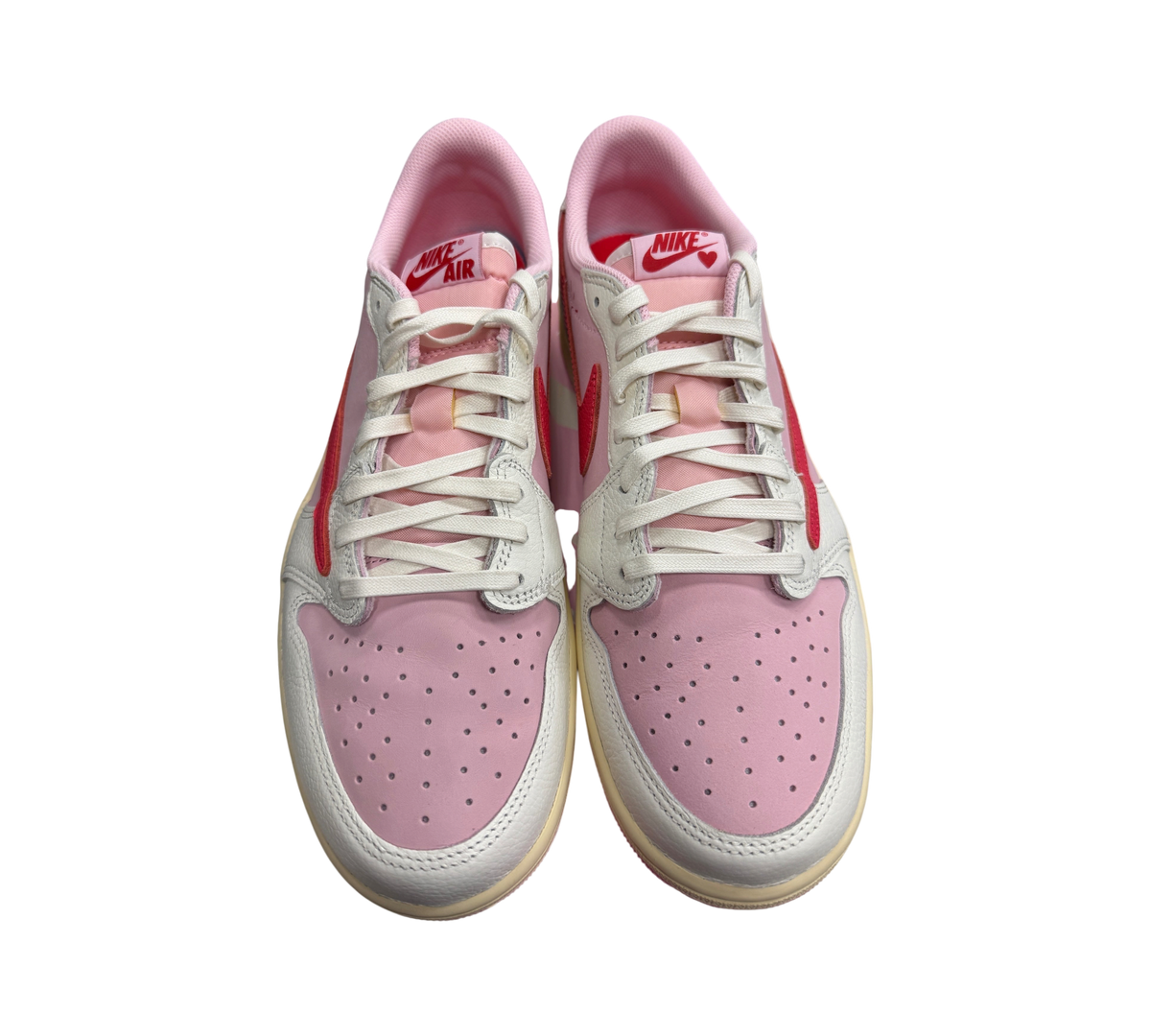 Genesis Boutique Jordan 1 Low Travis Scott Tropical Pink sneakers featuring pink leather, red swooshes, and white laces.
