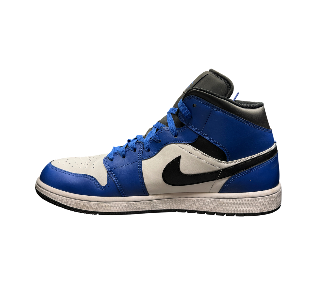 Genesis Boutique Jordan 1 Mid Game Royal sneakers in blue, white, and black leather displayed in a retail store.