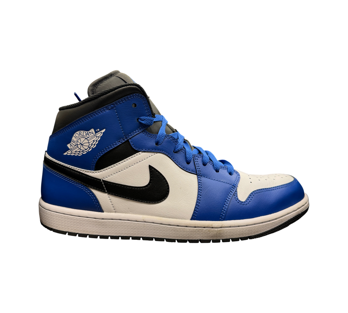 Genesis Boutique Jordan 1 Mid Game Royal sneakers in blue, black, and white leather on a glass display shelf