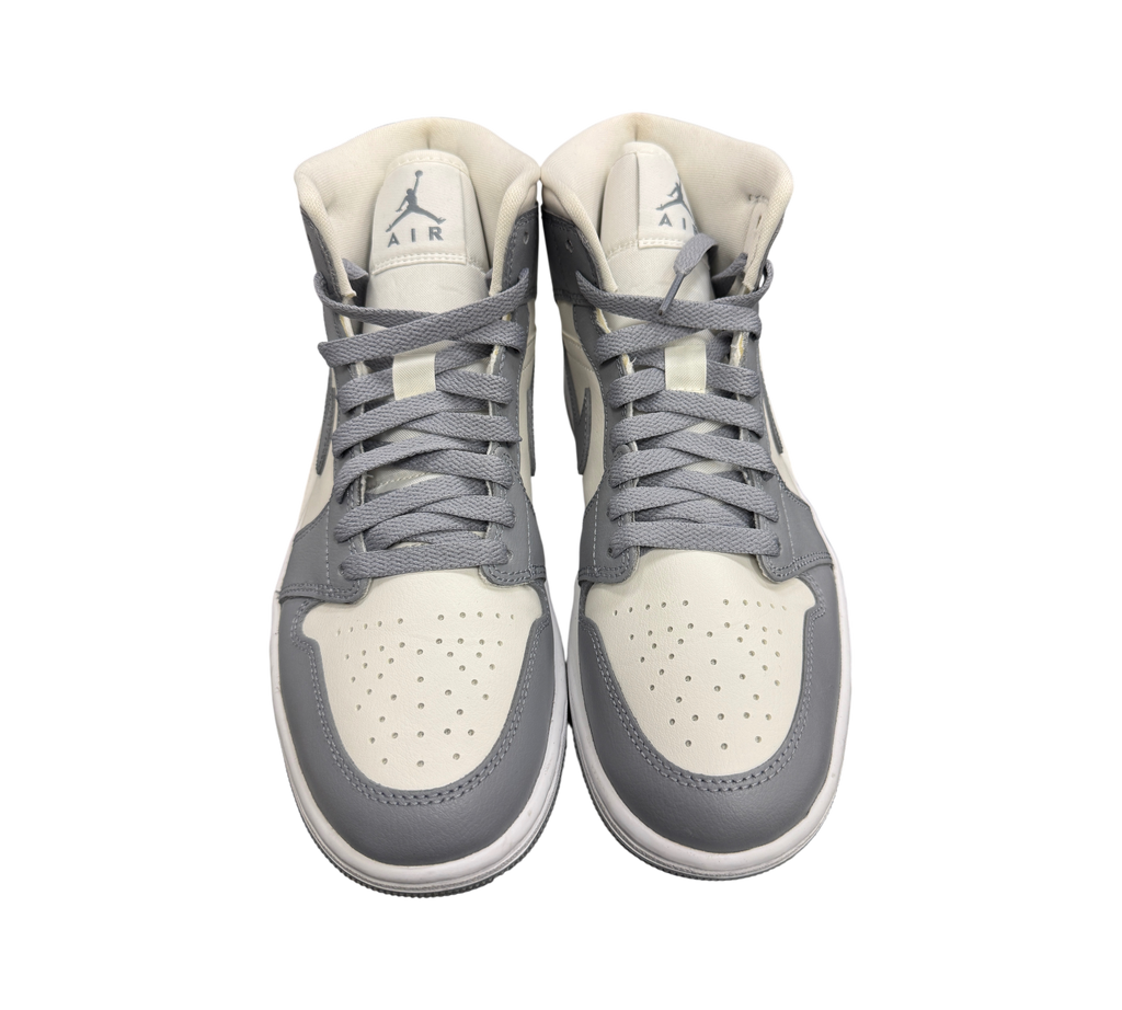 Genesis Boutique Jordan 1 Mid Stealth sneakers in grey and white leather with lace-up closure and Jumpman branding.