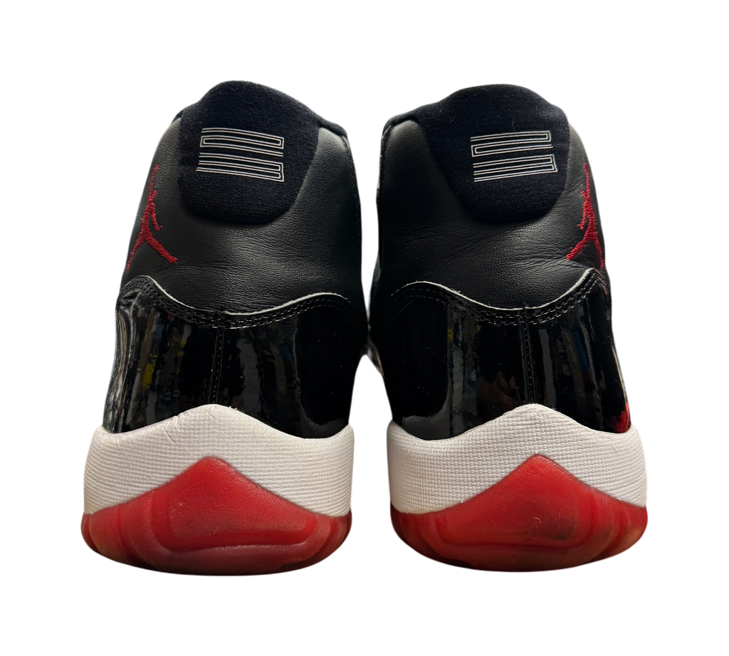 Genesis Boutique pre-owned Jordan 11 Bred 2019 sneakers showing black patent leather, red outsoles, and 23 heel detail.