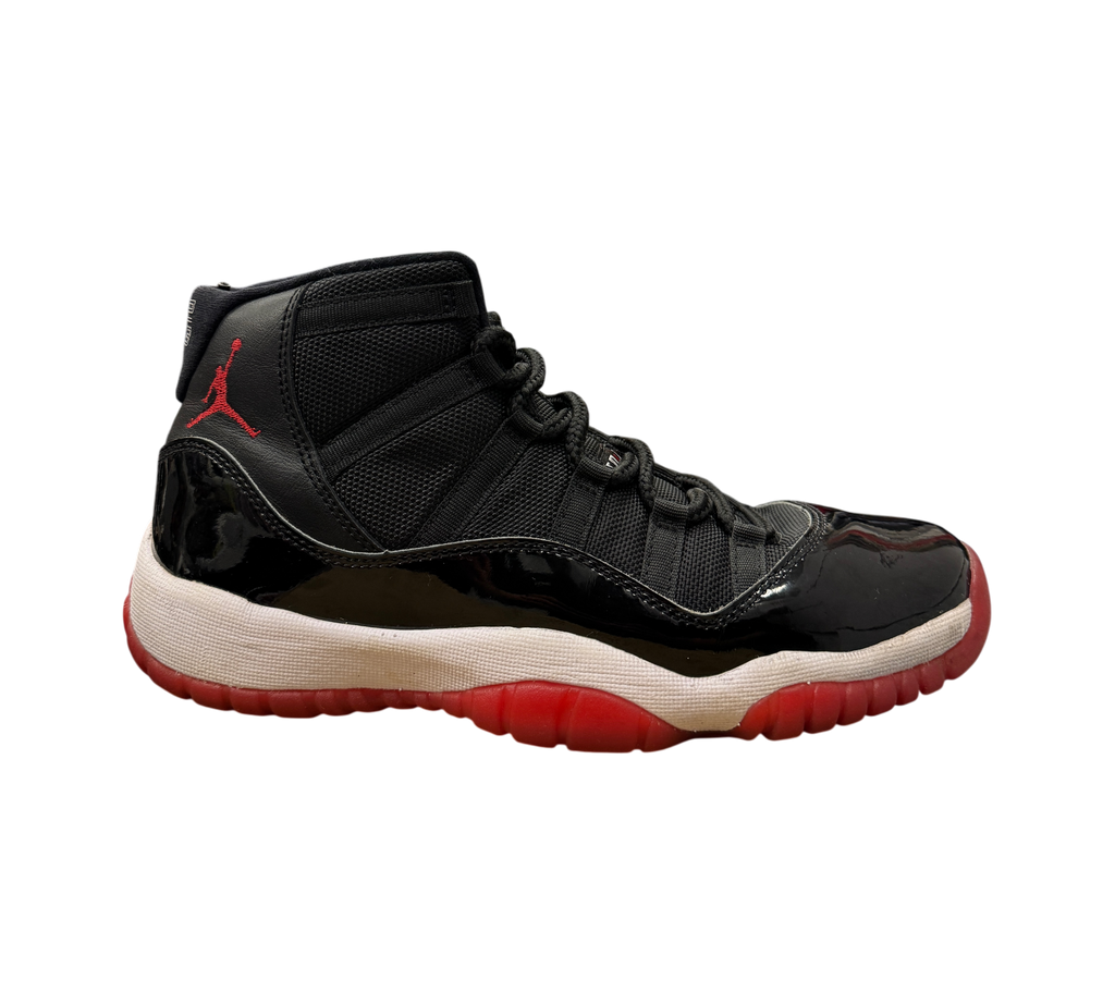 Genesis Boutique Jordan 11 GS Bred sneakers in black patent leather and mesh with a red Jumpman logo and red outsole.