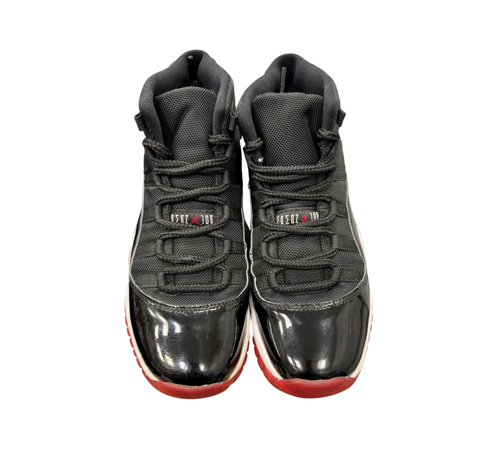 Genesis Boutique Jordan 11 GS Bred sneakers featuring black mesh, patent leather, and a red outsole.