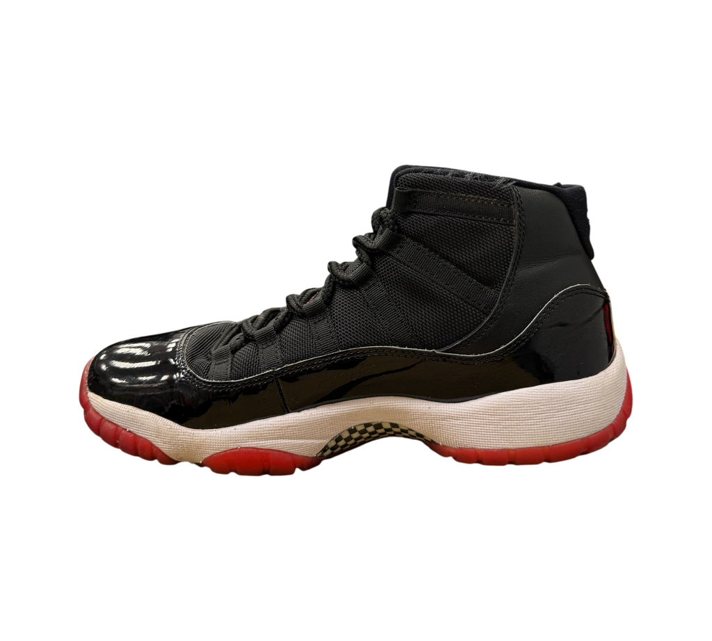 Genesis Boutique Jordan 11 GS Bred sneakers featuring a black patent leather upper and a red rubber outsole.