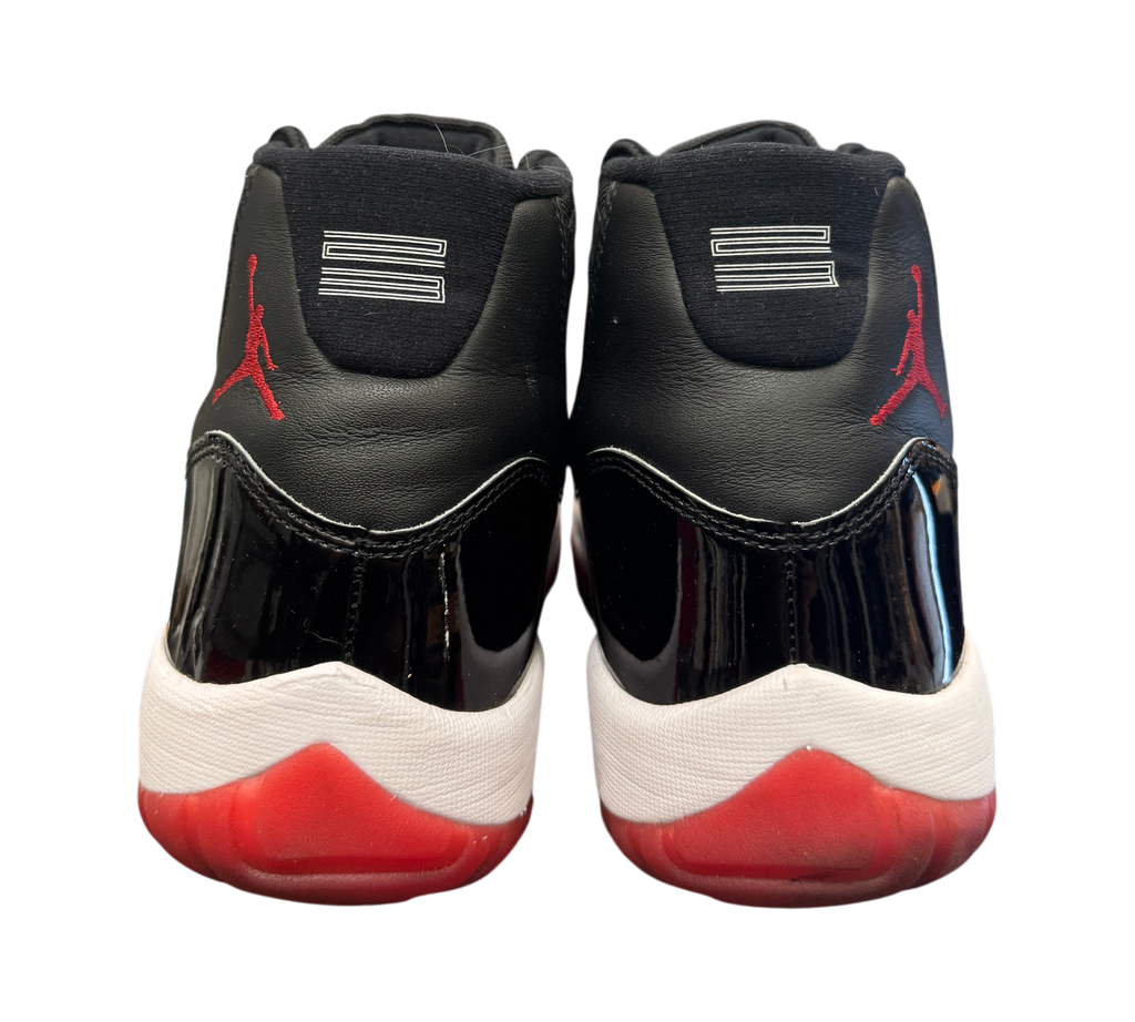 Genesis Boutique pre-owned Jordan 11 Bred 2019 sneakers showing black leather heels and red translucent outsoles