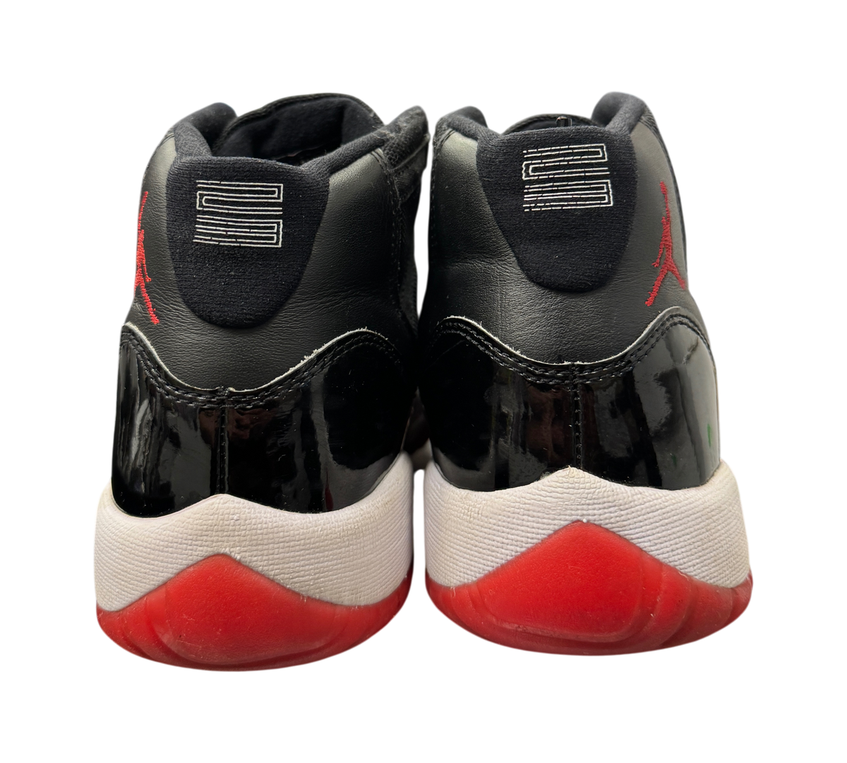 Genesis Boutique Jordan 11 GS Bred sneakers showing the black patent leather heels and red outsoles from the back.