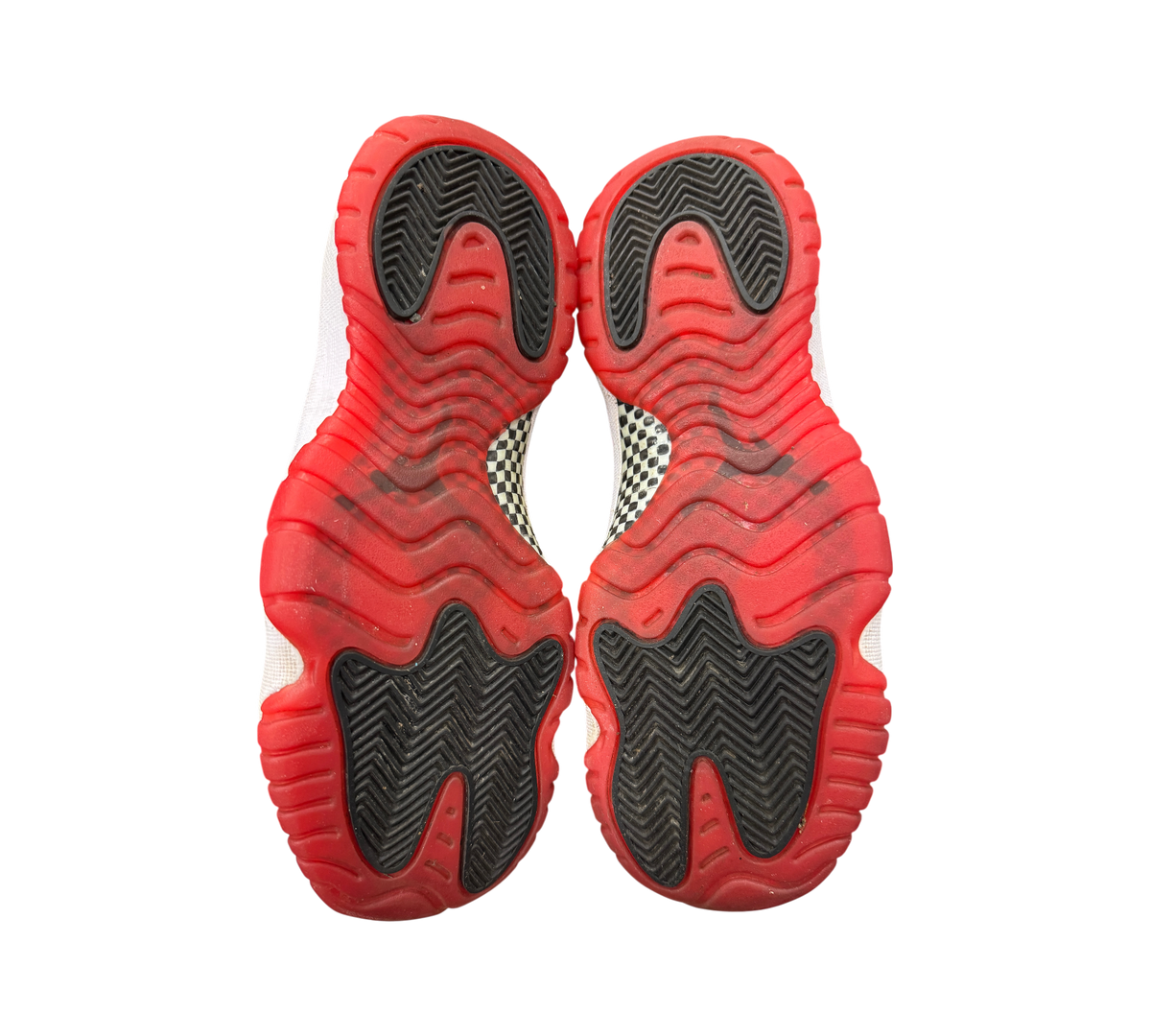 Genesis Boutique Jordan 11 GS Bred sneakers showing the red and black rubber outsoles with carbon fiber plate detail