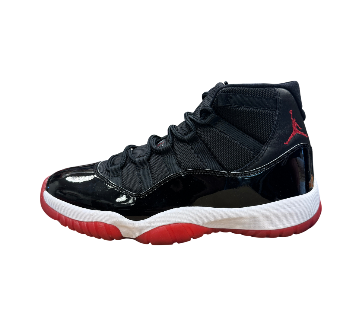 Genesis Boutique Jordan 11 Bred sneaker in black patent leather and mesh with a red outsole and Jumpman logo