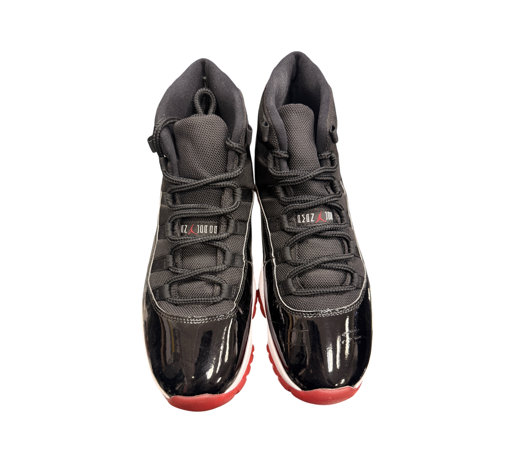 Genesis Boutique Jordan 11 2019 Bred sneakers with black mesh and patent leather uppers and red soles.