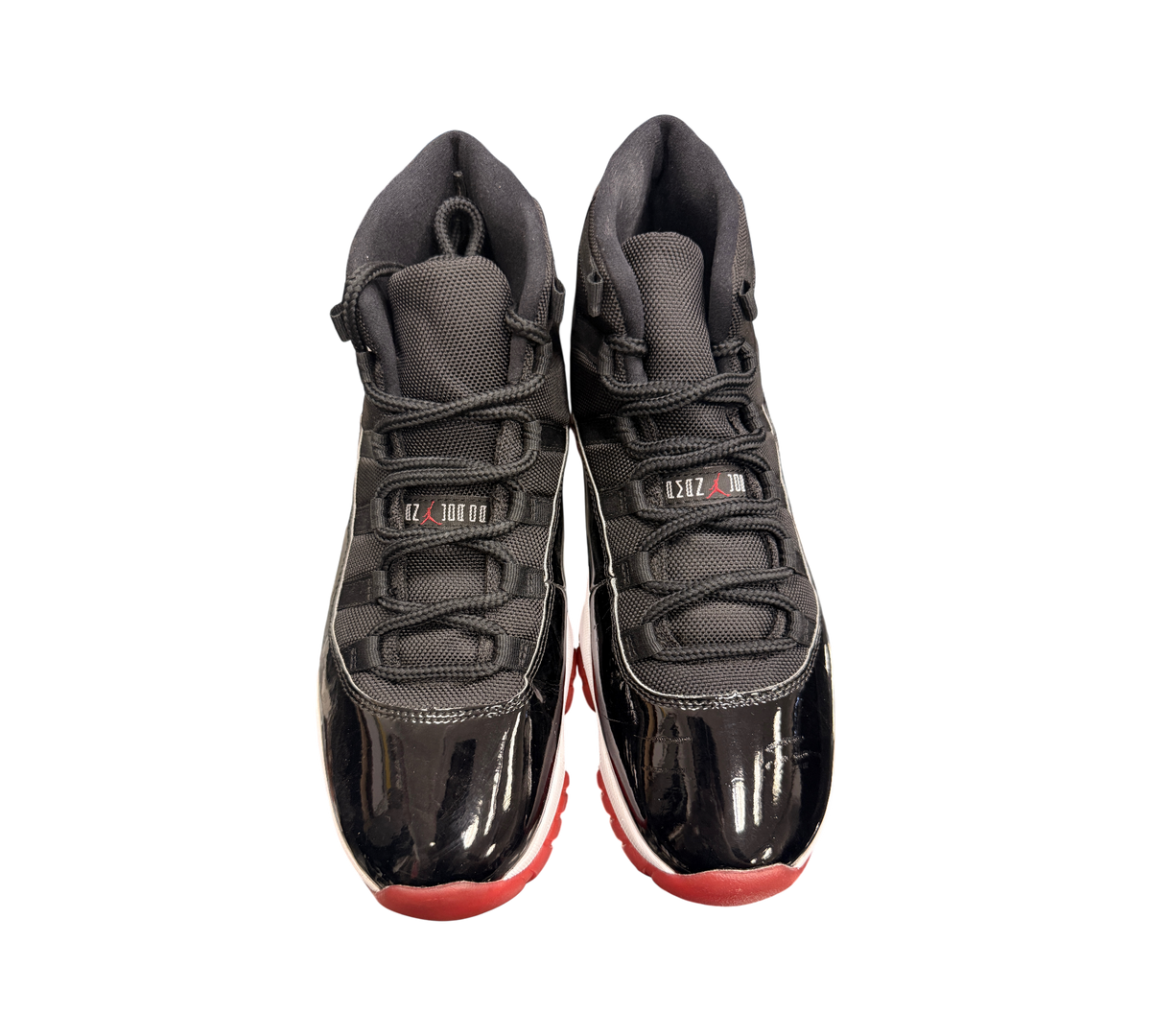 Genesis Boutique Jordan 11 2019 Bred sneakers with black mesh and patent leather uppers and red soles.