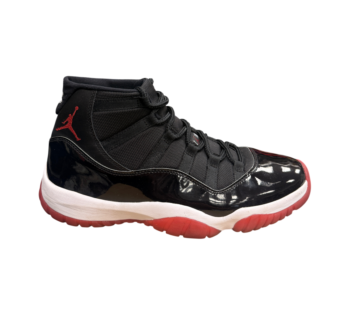 Genesis Boutique Jordan 11 2019 Bred sneakers with black mesh upper, patent leather mudguard, white midsole, and red outsole.