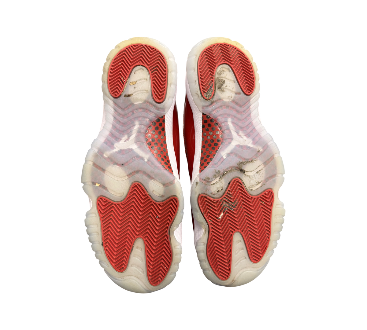 Used Jordan 11 Cherry sneakers from Genesis Boutique showing the red and translucent rubber outsoles with tread detail.