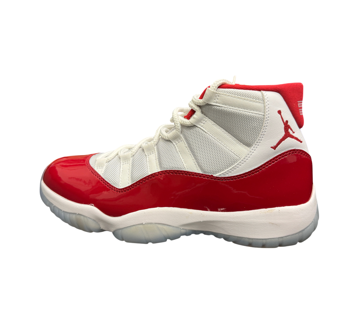 Genesis Boutique Jordan 11 Cherry sneaker with white mesh upper, red patent leather mudguard, and translucent outsole.