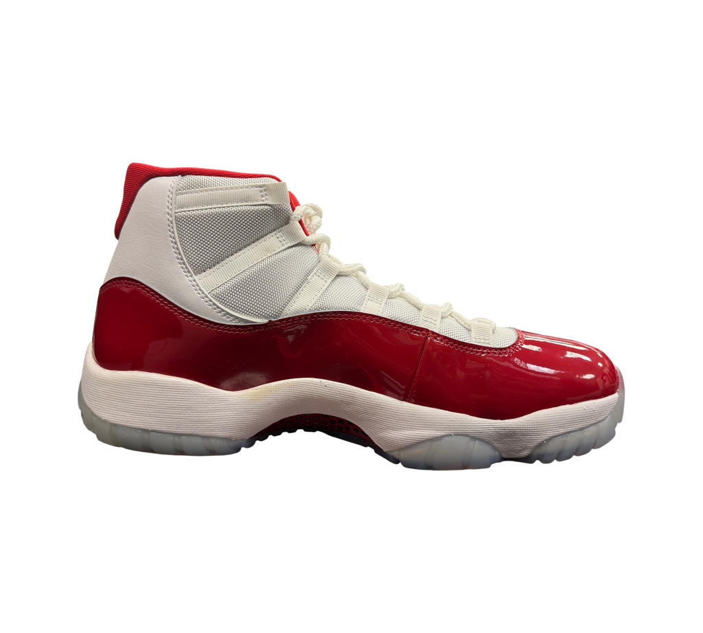 Genesis Boutique Jordan 11 Cherry sneakers featuring white mesh upper, red patent leather mudguard, and translucent sole