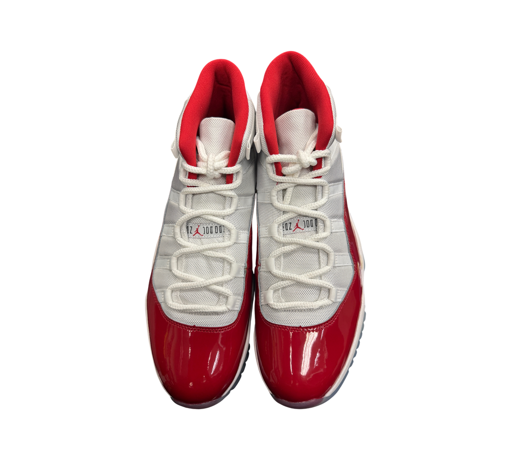Genesis Boutique Jordan 11 Cherry sneakers featuring white mesh uppers, red patent leather mudguards, and red lining.