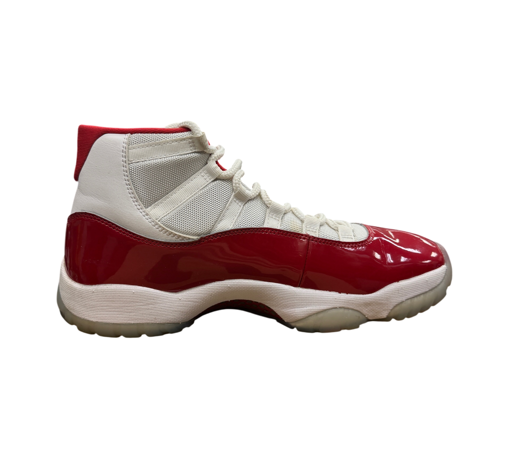 Genesis Boutique Jordan 11 Cherry sneakers in white and red patent leather, side profile view in a retail store.