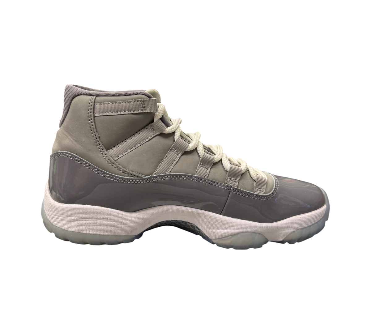 Genesis Boutique Jordan 11 Cool Grey sneakers featuring grey nubuck, patent leather, and white laces in a retail shop.