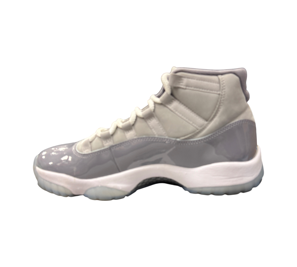 Genesis Boutique staff member holding a pair of Jordan 11 Cool Grey sneakers with patent leather and grey suede
