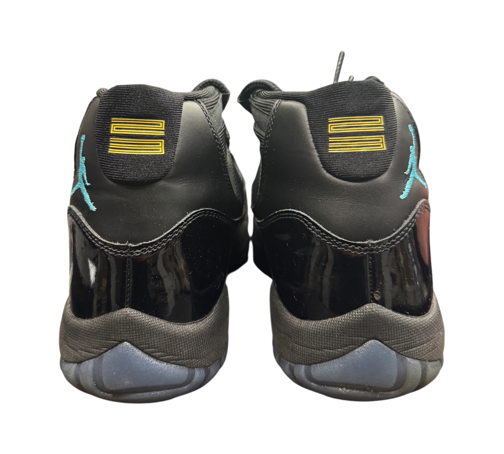 Genesis Boutique Jordan 11 Gamma sneakers featuring black patent leather, blue Jumpman logo, and yellow 23 heel detail