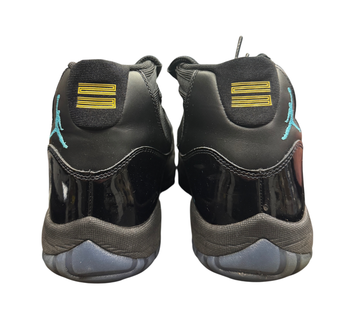 Genesis Boutique Jordan 11 Gamma sneakers featuring black patent leather, blue Jumpman logo, and yellow 23 heel detail