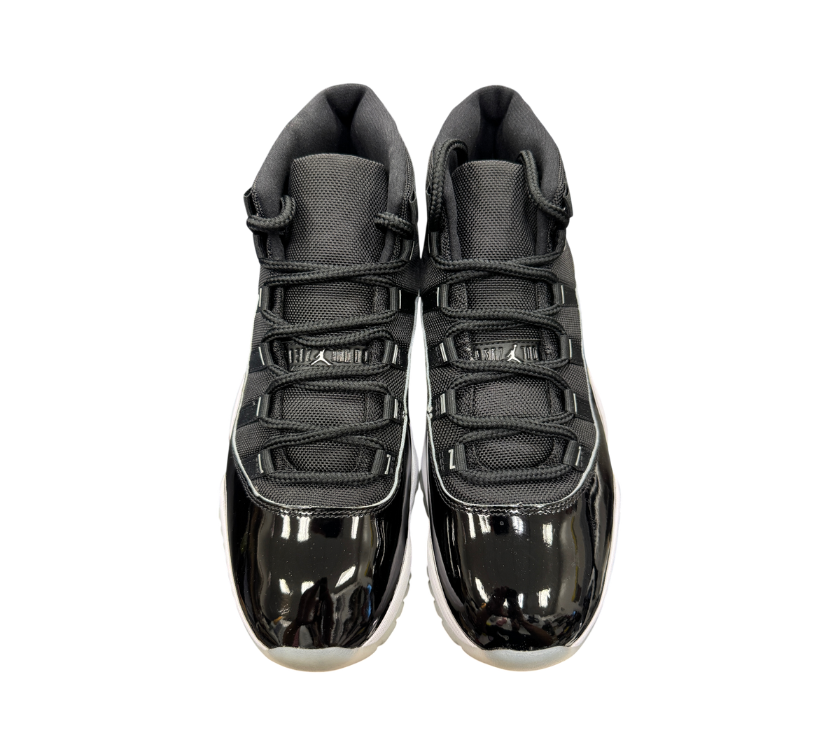 Genesis Boutique Jordan 11 Jubilee sneakers in black with patent leather mudguards and white midsoles, top view.