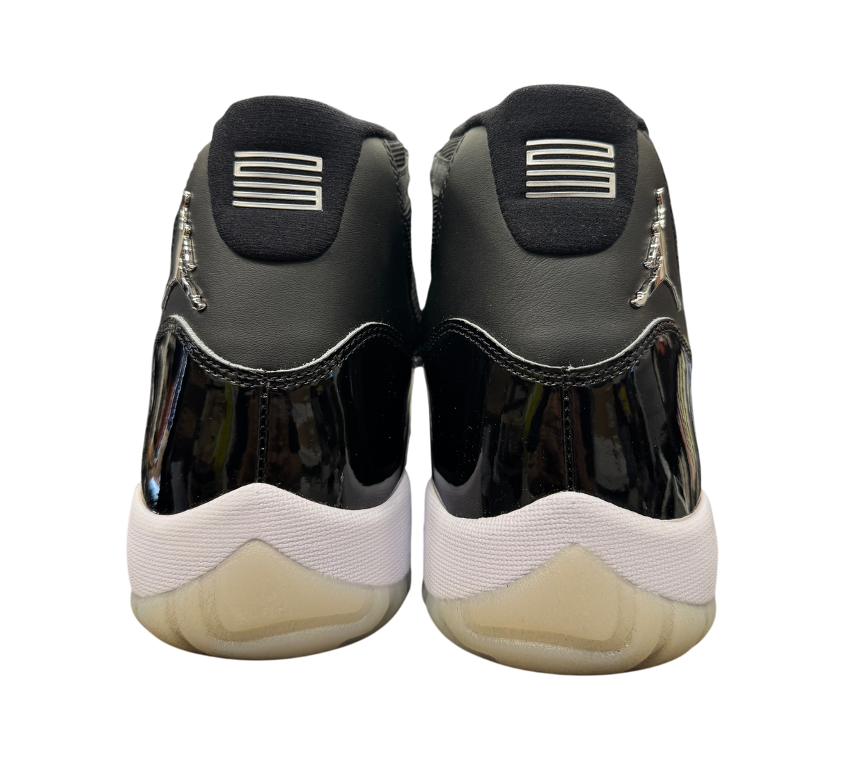 Genesis Boutique Jordan 11 Jubilee sneakers showing the black patent leather heels and silver Jumpman logos.
