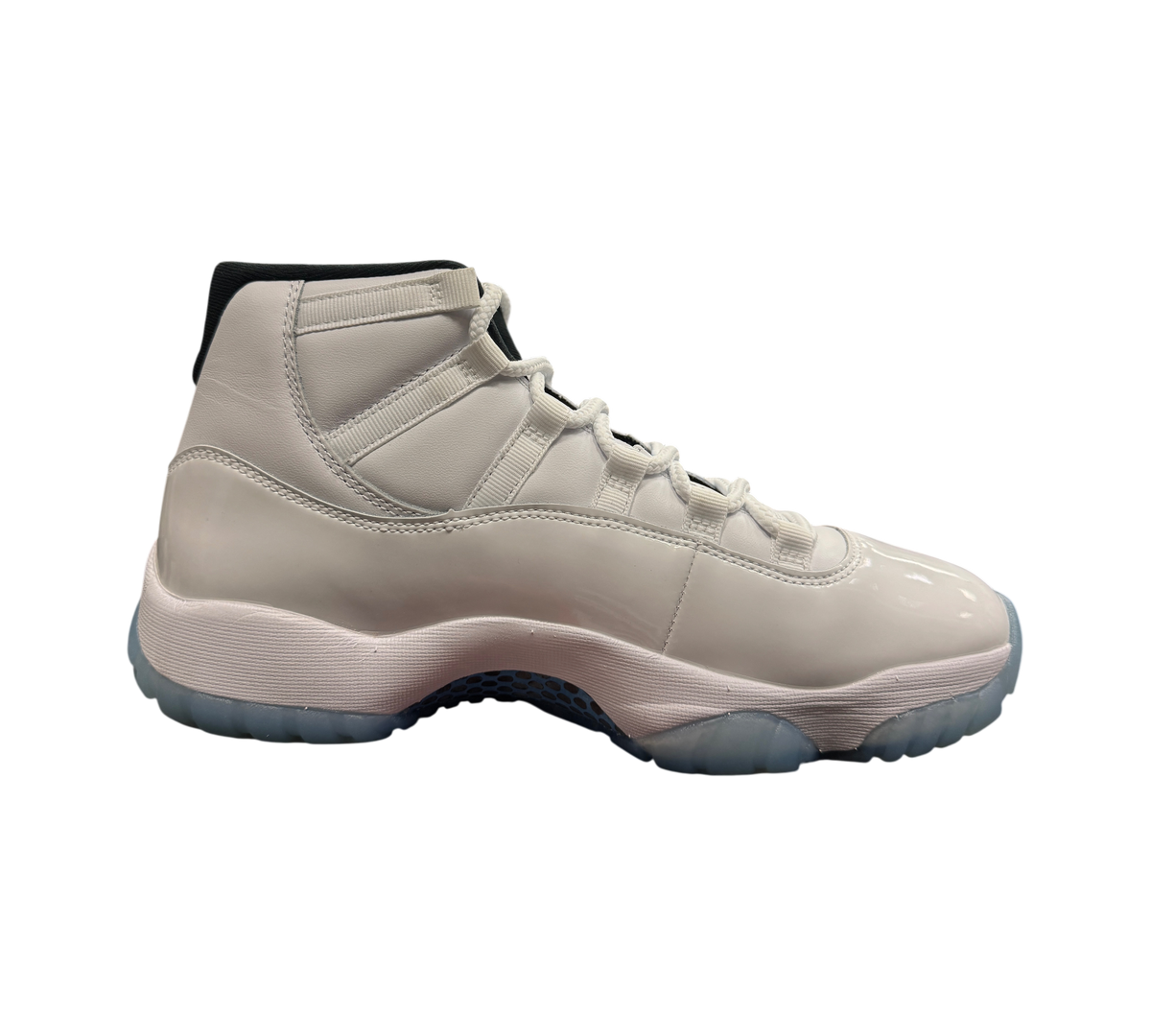 Genesis Boutique Jordan 11 Legend Blue sneaker in white patent leather with icy blue translucent sole, side view.