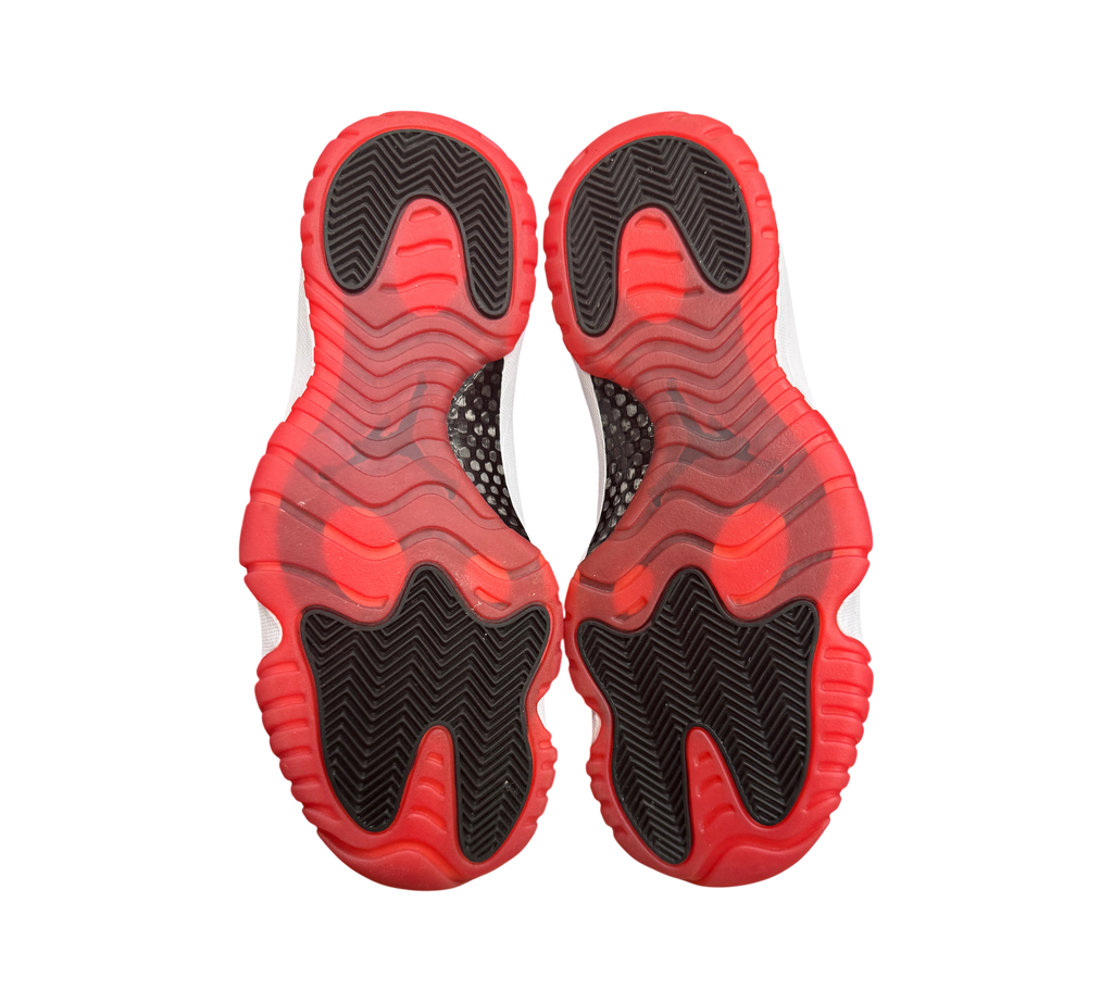Genesis Boutique used Jordan 11 Low Bred sneakers showing the red and black translucent rubber outsoles.
