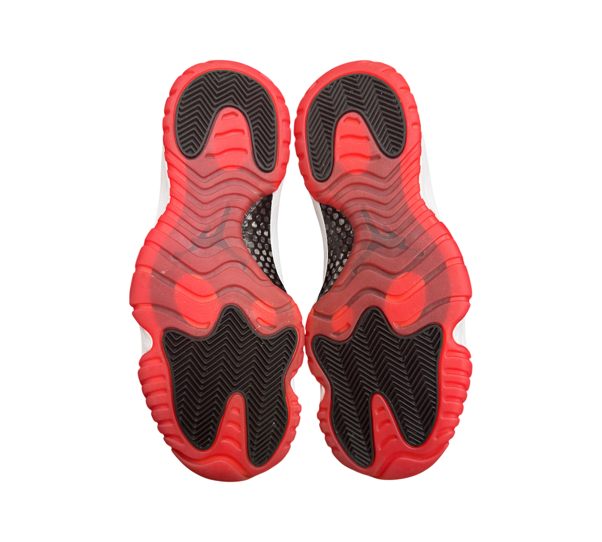 Genesis Boutique used Jordan 11 Low Bred sneakers showing the red and black translucent rubber outsoles.