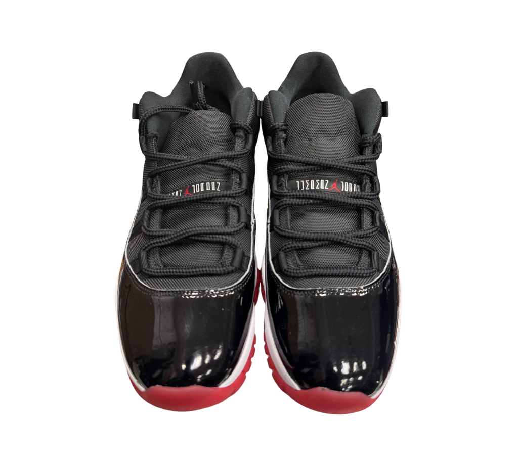 Genesis Boutique pre-owned Jordan 11 Low Bred sneakers featuring black patent leather, mesh upper, and red outsole.