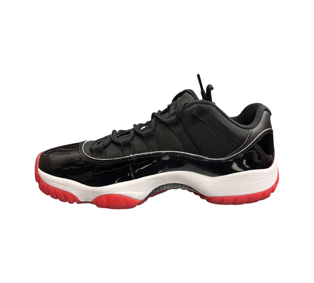 Genesis Boutique Jordan 11 Low Bred sneakers featuring black patent leather, mesh upper, white midsole, and red outsole.