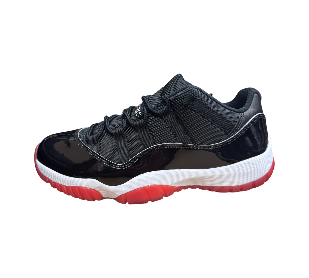 Genesis Boutique Jordan 11 Low Bred sneaker in black mesh and patent leather with a white midsole and red outsole.