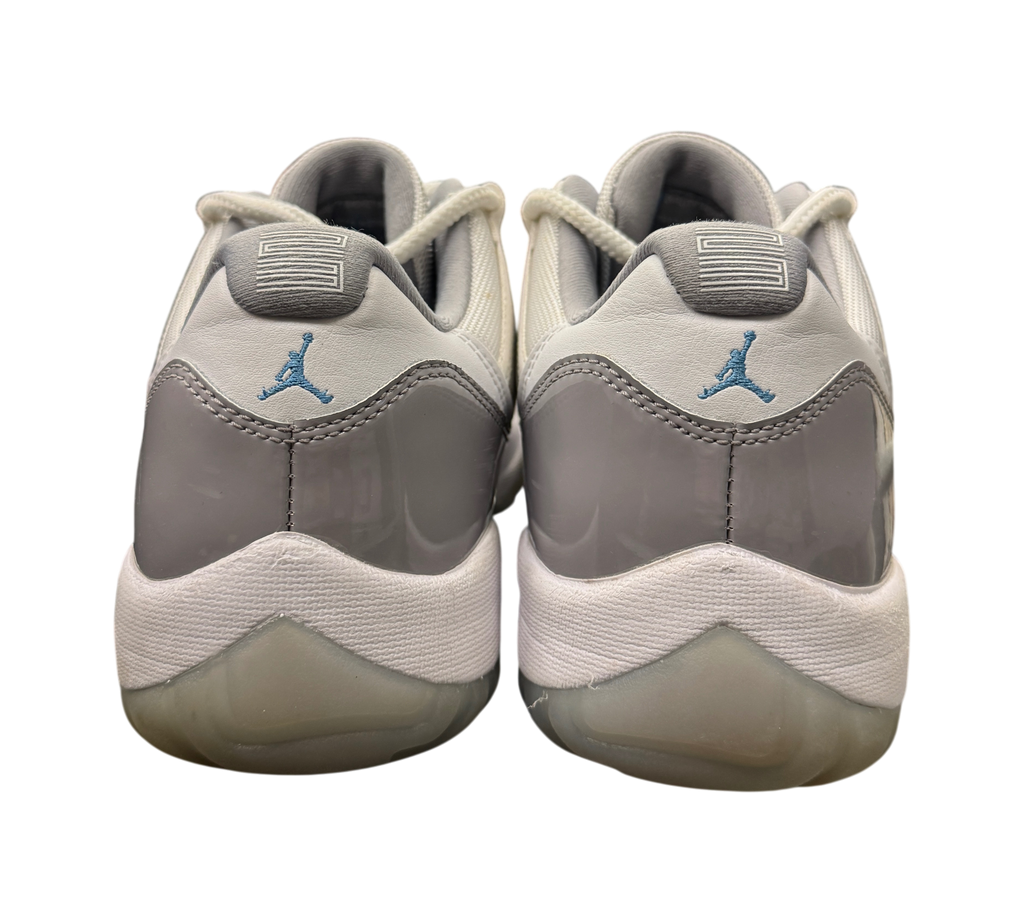 Genesis Boutique Jordan 11 Low Cement Grey sneakers with patent leather heel and blue Jumpman logo in a retail store.