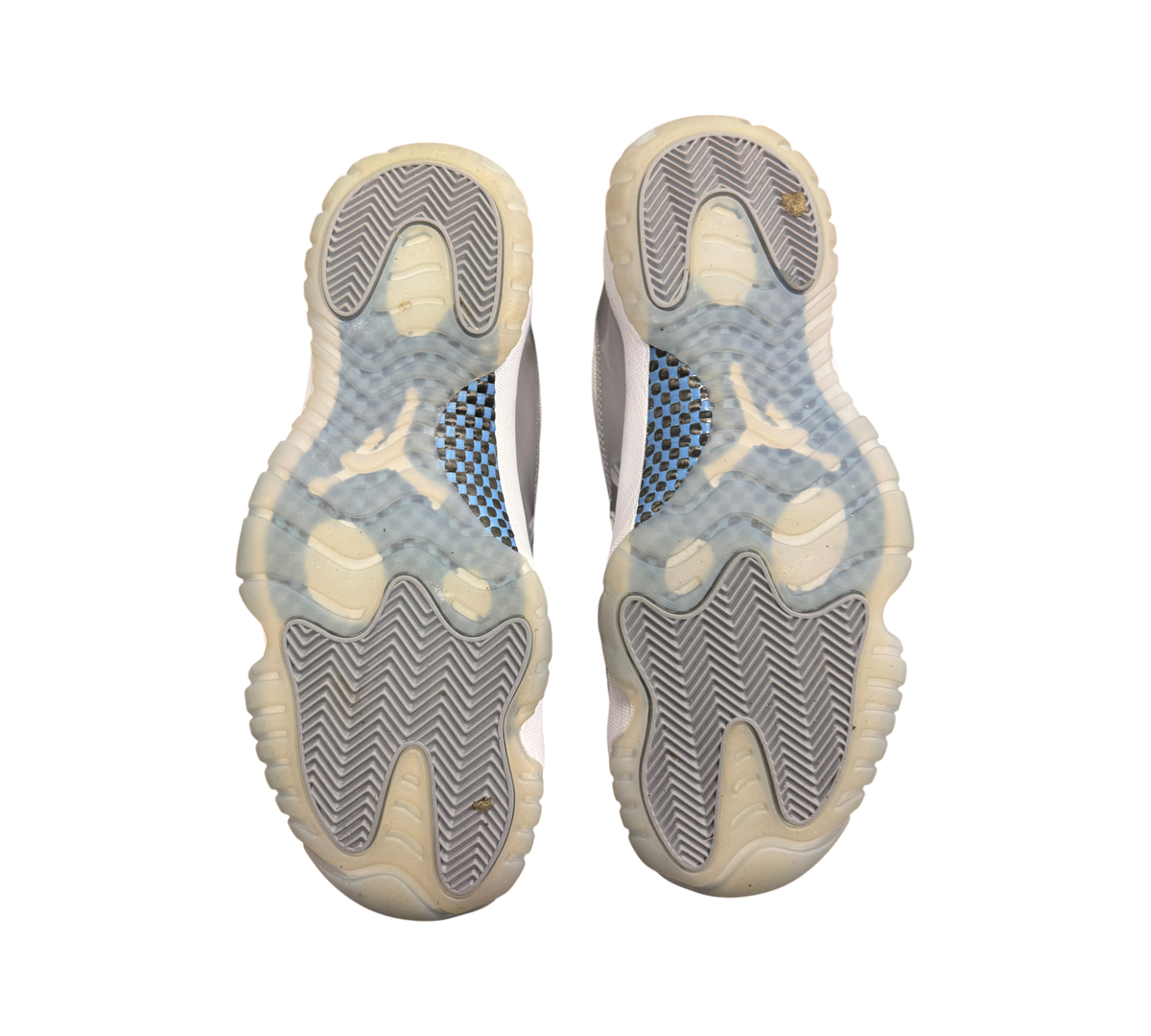 Genesis Boutique Jordan 11 Low Grey Cement sneakers showing the translucent outsoles with carbon fiber plate detail.