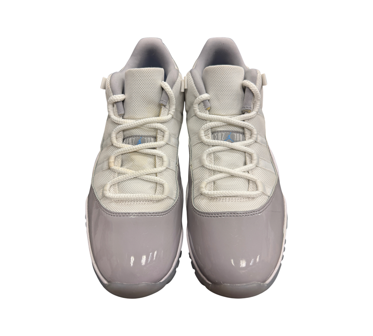 Genesis Boutique Jordan 11 Low Grey Cement sneakers featuring white mesh uppers, grey patent leather, and blue accents.