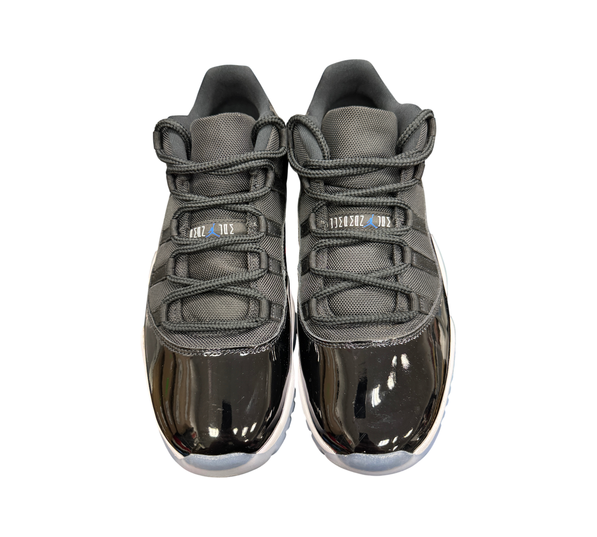 Genesis Boutique Jordan 11 Low Space Jam sneakers featuring black mesh uppers, patent leather mudguards, and blue logos.