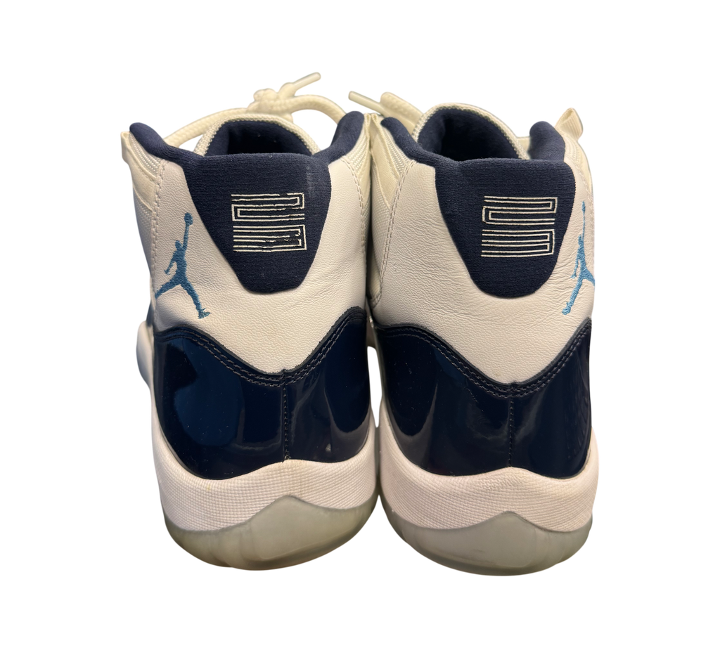 Genesis Boutique Jordan 11 "Win Like 82" shoes with white leather, navy patent leather, and light blue accents.