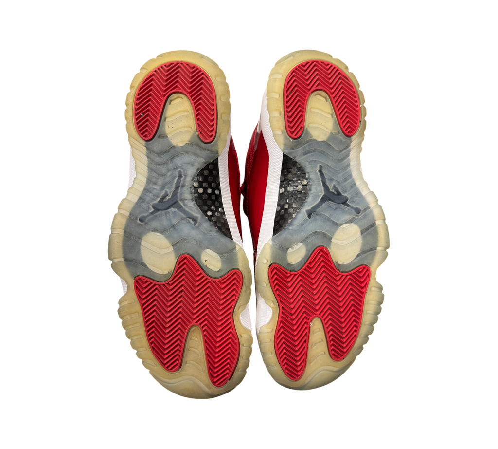 Genesis Boutique Jordan 11 Win Like 96 sneakers showing red and translucent rubber outsoles from a bottom view