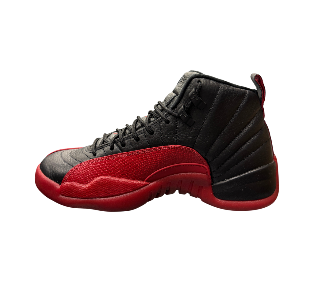 Genesis Boutique Jordan 12 Flu Game 2025 sneakers in black and red leather displayed on a glass shelf in a store.