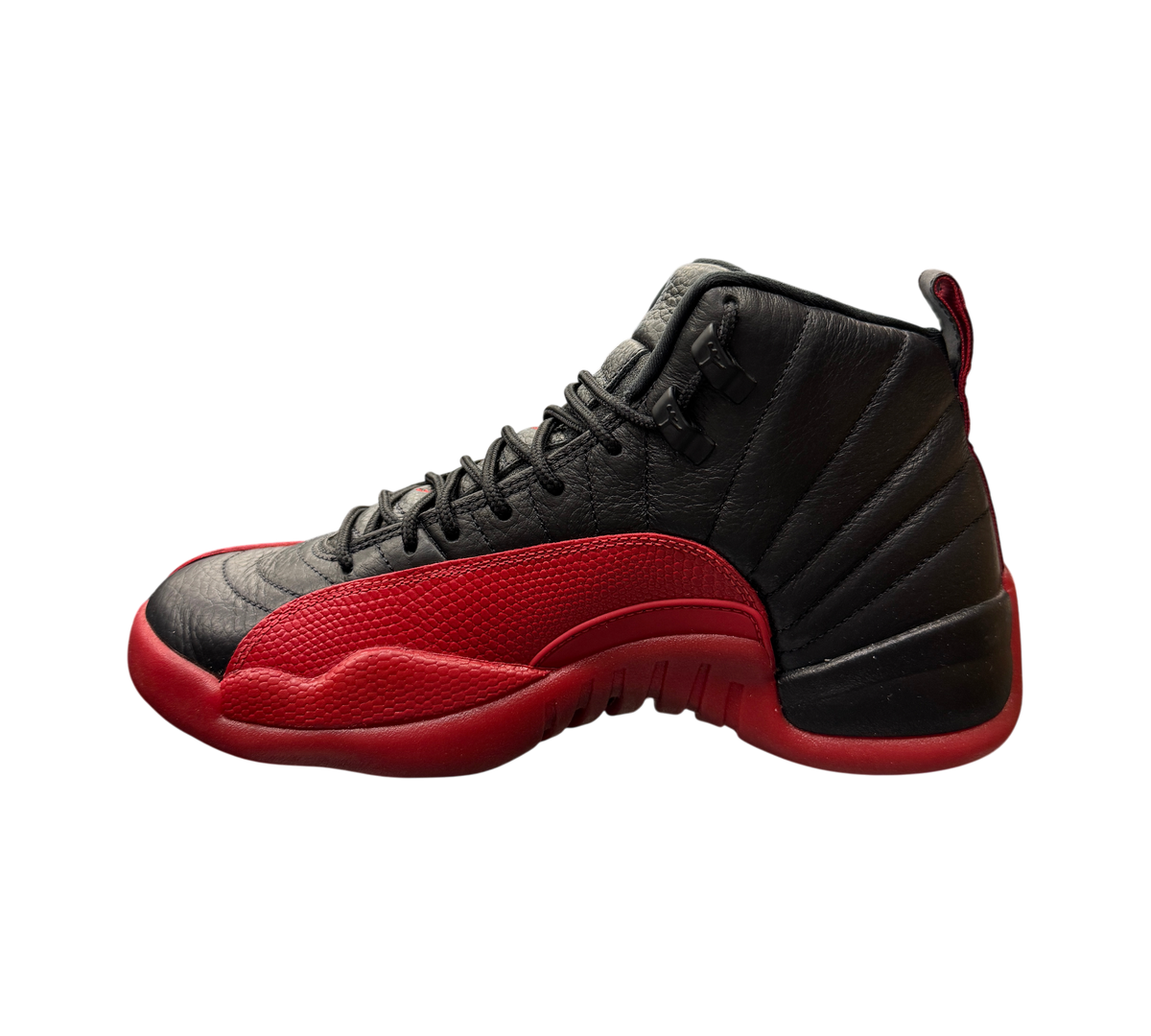 Genesis Boutique Jordan 12 Flu Game 2025 sneakers in black and red leather displayed on a glass shelf in a store.