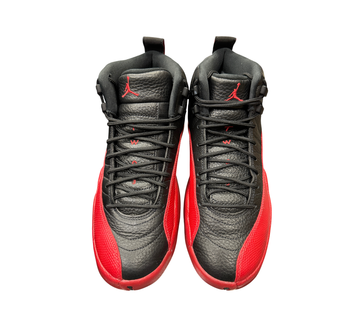 Genesis Boutique Jordan 12 Flu Game 2025 sneakers in black and red leather with iconic textured mudguard design.